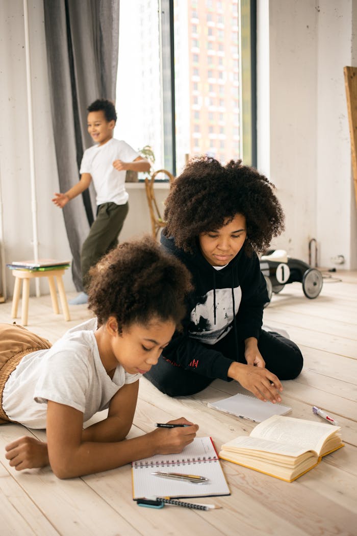 Mother helps daughter with homework while son plays indoors, focusing on education and family bonding.